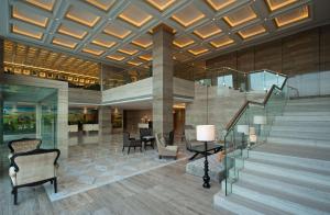 a lobby with a staircase and chairs and tables at Hyatt Regency Ludhiana in Ludhiana