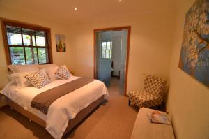 a bedroom with a large bed and a chair at Stone Creek Cottage in Barwite