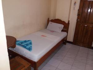 a small bedroom with a bed with white sheets at Bee Hub Pension in Surigao