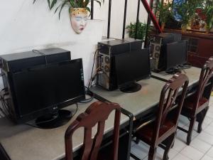 曼谷的住宿－普拉蘇瑞旅館，上面有三个电脑显示器的桌子