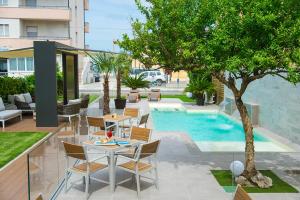 un patio con mesa y sillas junto a una piscina en Hotel Olimpia, en Bellaria-Igea Marina