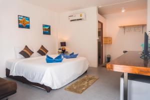 a bedroom with a white bed with blue pillows at Pink Easy Homes Koh Phangan in Thongsala