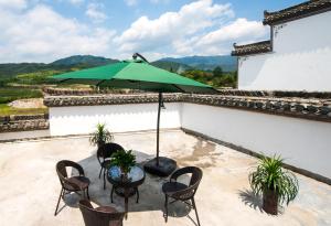 un patio con mesa, sillas y sombrilla en W_Smart Motel Superior Hongcun, en Yi