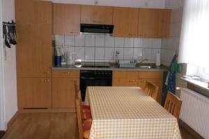 a kitchen with wooden cabinets and a table with a checkered table cloth at Peper Ute in Neustadt in Holstein