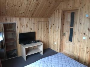 a bedroom with a bed and a tv in a wooden wall at Садиба Червона калина Private estate Chervona Kalyna in Yaremche