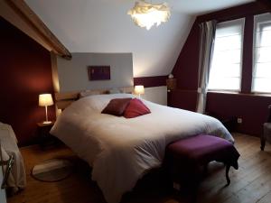 um quarto com uma grande cama branca com almofadas vermelhas em La Maison Brodée em Écaussinnes-dʼEnghien