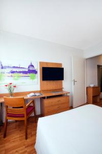 リヨンにあるセジュール＆アフェール リヨン サン ニコラのベッド、デスク、テレビが備わるホテルルームです。