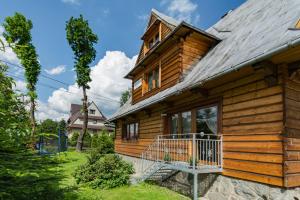 a log cabin with a porch and a balcony at Mazurkowy Gościniec in Zakopane