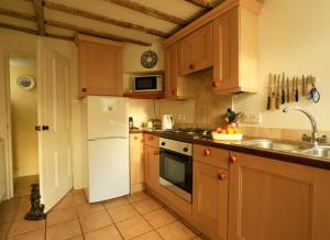 a kitchen with wooden cabinets and a white refrigerator at Church Lane Cottage in Llanidloes