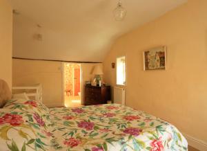 スランイドロイスにあるChurch Lane Cottageのベッドルーム1室(花柄のベッドカバー付きの大型ベッド1台付)