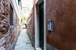 ヴェネツィアにあるCà Tolentiniのレンガ造りの建物内の緑の扉のある路地
