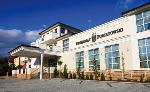 a white building with a sign on the front of it at Pensjonat Poniatowski in Suchowola