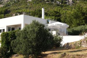 a white house with an umbrella on a hill at Open Hus in Krvavica
