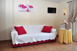 a living room with a white couch and red pillows at La Grande Malardiere in Saint-Georges-Buttavent