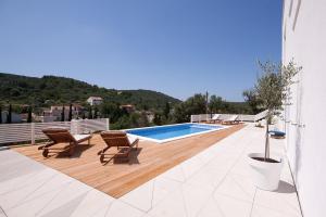 a swimming pool on a wooden deck with two chairs at Villa Artemis in Žman