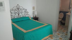 sypialnia z łóżkiem z zieloną kołdrą w obiekcie Hotel Residence Villa Igea Capri w mieście Capri