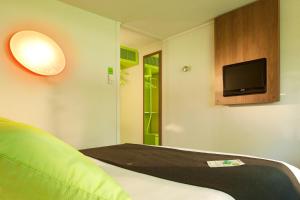 Cette chambre comprend un lit et une télévision à écran plat. dans l'établissement Campanile Valenciennes - Petite-Forêt, à Petite-Forêt
