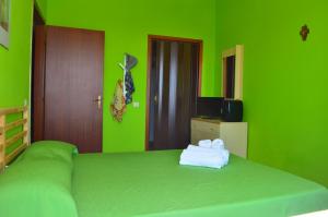 フォンターネ・ビアンケにあるVilla a Fontane Biancheの緑のベッドルーム(タオル付きのベッド付)