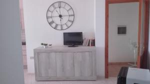 a room with a tv and a clock on the wall at Casa Dolores in Baunei