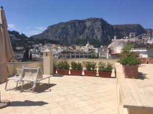 una sedia seduta in cima a un balcone con vista sulle montagne di Hotel Residence Villa Igea Capri a Capri