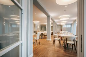 a dining room with white tables and chairs at Aparthotel Touring in Grado
