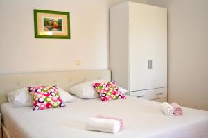 Un dormitorio con una cama blanca con almohadas rosas y blancas en Apartments Ivica, en Makarska