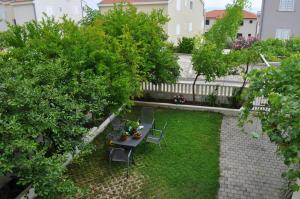un jardín con mesa, sillas y árboles en Apartments Ivica, en Makarska