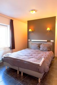 B&B De Fruithoeve في Hoeselt: سرير في غرفة نوم مع مصباحين على الحائط