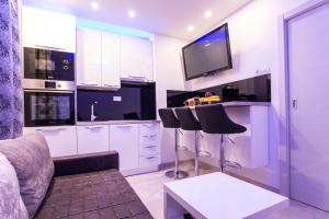 a kitchen with white cabinets and a tv and a couch at Apartman M.E.P. in Split