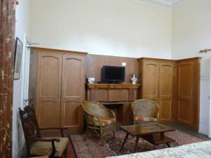 een woonkamer met een tv en een tafel en stoelen bij Heritage Homestay in Jammu