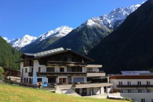 a building on a hill with mountains in the background at Frühstückspension Astoria in Sölden