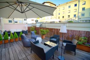 eine Terrasse mit Stühlen, Tischen und einem Sonnenschirm in der Unterkunft Rheinland Hotel in Bonn
