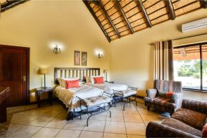 two beds in a room with a couch and chairs at Zebula Golf Estate & Spa Executive Holiday Homes in Mabula