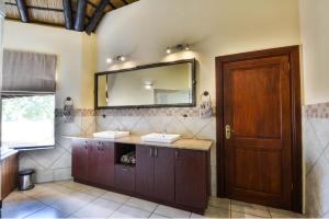 a bathroom with two sinks and a mirror at Zebula Golf Estate & Spa Executive Holiday Homes in Mabula