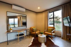 a living room with a desk and chairs and a mirror at Zebula Golf Estate & Spa Executive Holiday Homes in Mabula