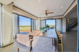 a dining room with a long table and chairs at Zebula Golf Estate & Spa Executive Holiday Homes in Mabula