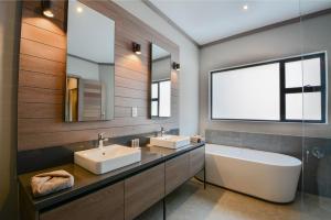 a bathroom with two sinks and a large mirror at Zebula Golf Estate & Spa Executive Holiday Homes in Mabula