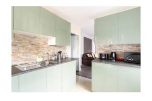 een keuken met witte kasten en een woonkamer bij treetops flat3 Hall Green B28 in Birmingham