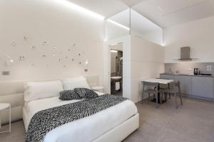 a white bedroom with a bed and a kitchen at Nostos rooms & Apartments in Syracuse