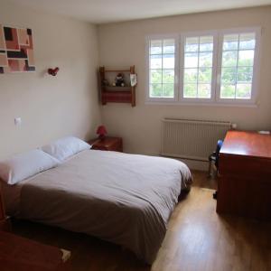 a bedroom with a large bed and two windows at au jardin Fessard in Fagnon