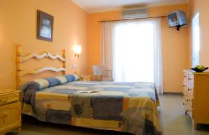 - une chambre avec un lit, une commode et une fenêtre dans l'établissement Hotel Es Furió, à Tamariu