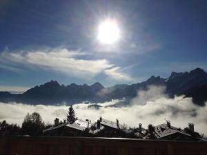 una vista del sol sobre las nubes y las montañas en Hotel La Caminatha en Val di Zoldo