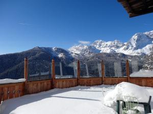 uma cerca de madeira com montanhas nevadas ao fundo em Hotel La Caminatha em Val di Zoldo
