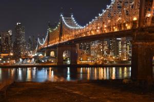 a city at night with a bridge over it at Ravel Hotel Trademark Collection by Wyndham in Queens