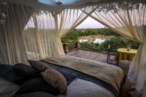 a bedroom with a bed on a deck with a view at Garonga Safari Camp in Makalali Game Reserve