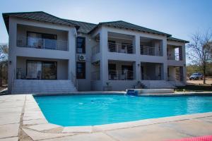a house with a swimming pool in front of a house at Tinyiko Kruger Lodge in Marloth Park