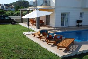 two chairs and an umbrella next to a pool at Villa Arance in Fethiye