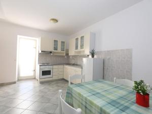 a kitchen with a table and a white refrigerator at Pleasant Apartment in Zidarici near the Sea in Malinska