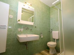 a green tiled bathroom with a sink and a toilet at Pleasant Apartment in Zidarici near the Sea in Malinska