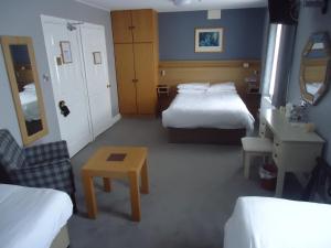 a hotel room with two beds and a desk and a table at Templemore Arms Hotel in Templemore
